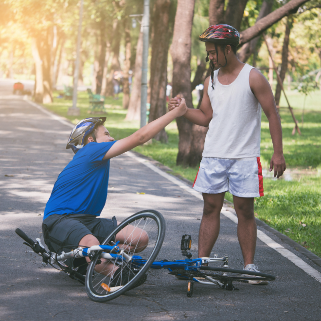 Cyclist carrying a damaged bicycle wheel after a crash