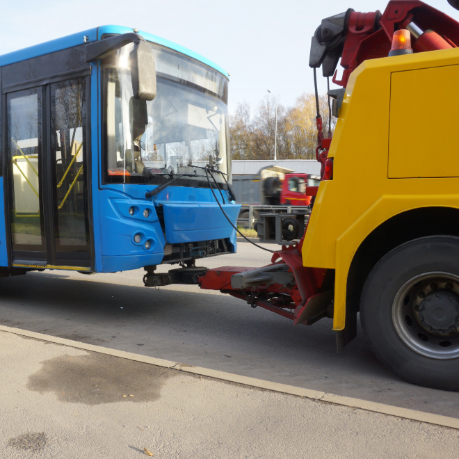 Disabled city bus being towed after a crash