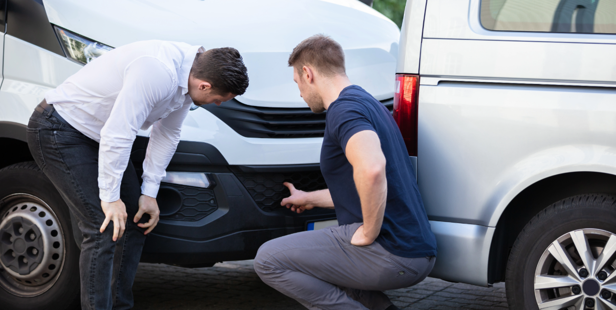 Drivers inspecting commercial van bumper damage