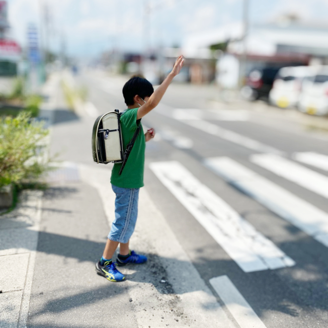 Child waiting at a crosswalk with a backpack