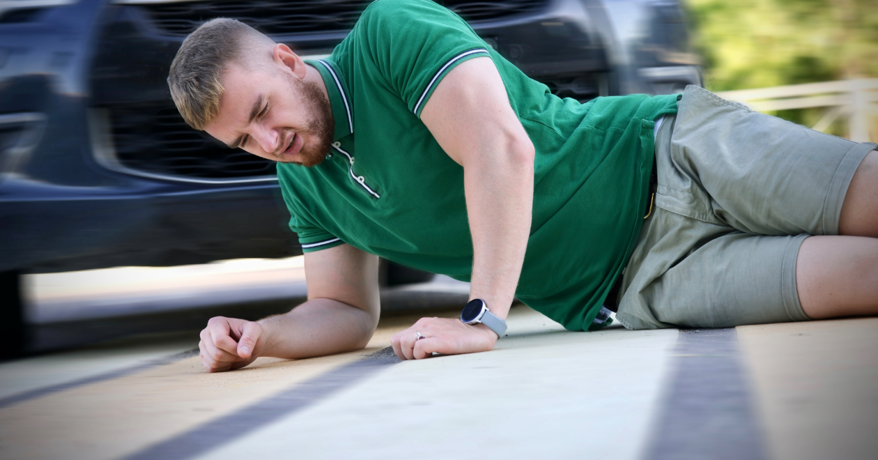 Injured pedestrian on pavement beside a car