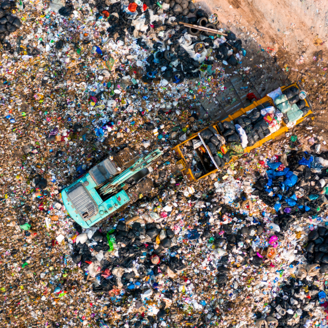 Aerial view of a garbage truck in a landfill waste field