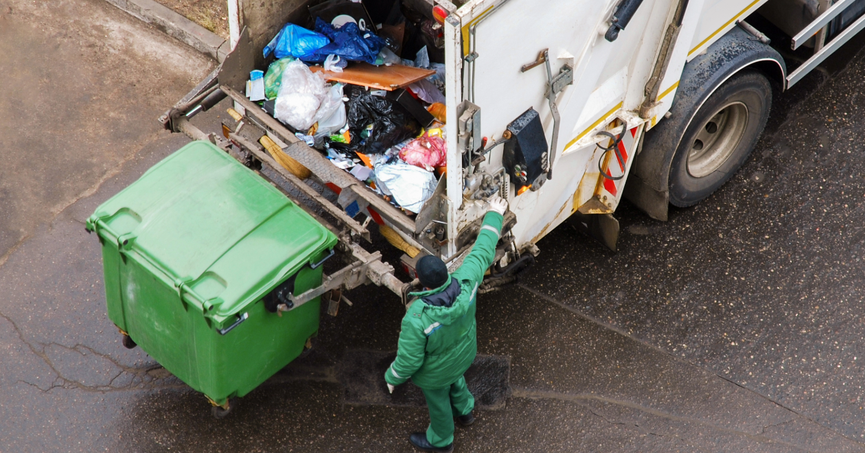Sanitation worker emptying a bin into a garbage truck