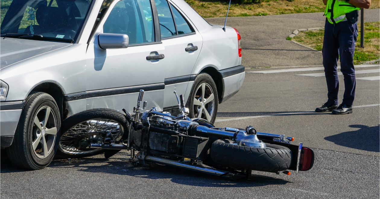 Motorcycle down beside a sedan with an officer nearby